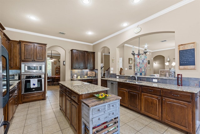 5024 Running Brook Dr, Joshua, TX 76058 - kitchen featuring stainless steel appliances, arched walkways, light tile patterned floors, a kitchen island, and ornamental molding