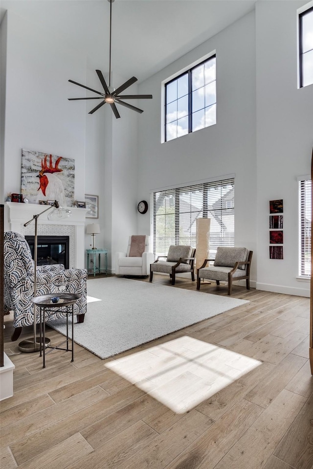 2128 Eastleigh Dr, Fort Worth, TX 76008 - living room featuring a towering ceiling, ceiling fan, light wood-style floors, and a tiled fireplace
