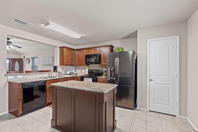 1420 Arabella Ave, Forney, TX 75126 - kitchen with black appliances, light tile patterned floors, a kitchen island, and light stone counters