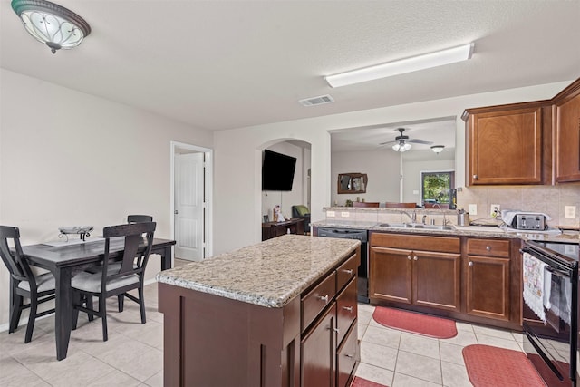 1420 Arabella Ave, Forney, TX 75126 - kitchen featuring black appliances, light tile patterned floors, arched walkways, a kitchen island, and a peninsula