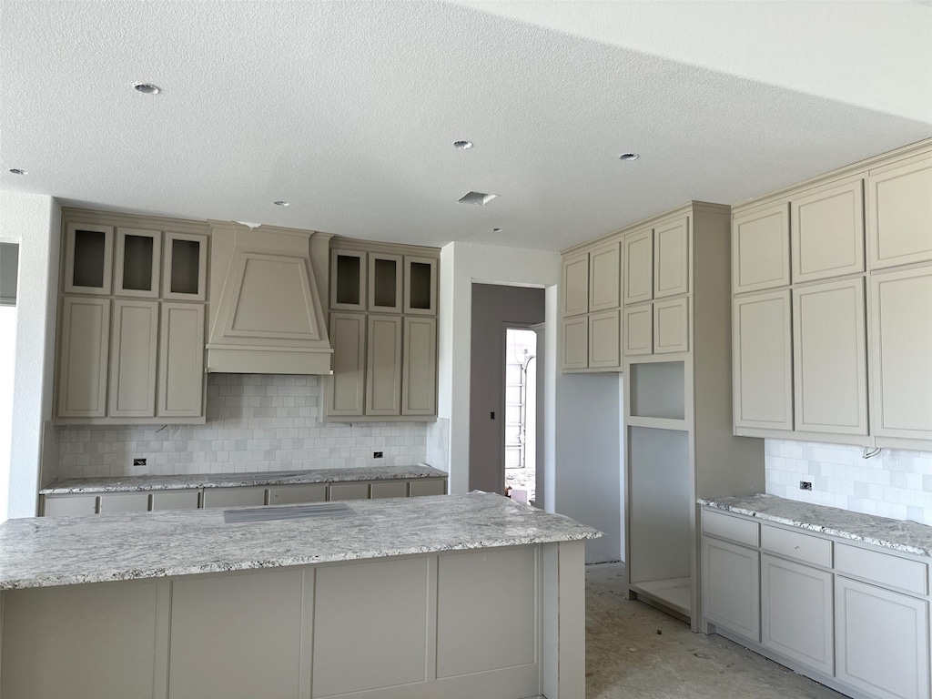 150 Waterview, Gunter, TX 75058 - kitchen featuring custom range hood, backsplash, a textured ceiling, cream cabinets, and light stone countertops