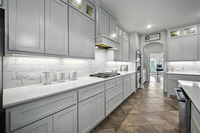 9840 El Colina Dr, Fort Worth, TX 76179 - kitchen with stainless steel appliances, tasteful backsplash, arched walkways, light countertops, and glass insert cabinets