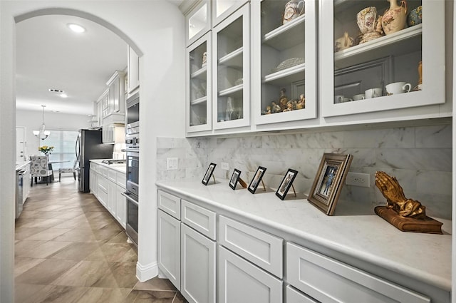 9840 El Colina Dr, Fort Worth, TX 76179 - bar area featuring arched walkways, backsplash, stainless steel appliances, and decorative light fixtures