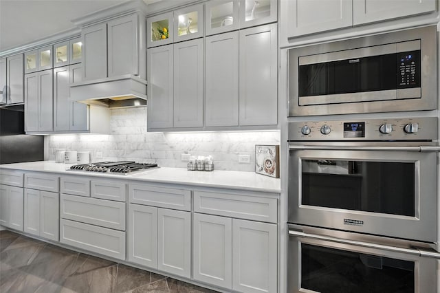 9840 El Colina Dr, Fort Worth, TX 76179 - kitchen featuring stainless steel appliances, light countertops, backsplash, glass insert cabinets, and premium range hood
