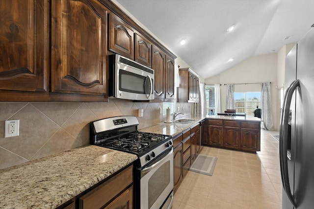 10200 Wildfowl Dr, Fort Worth, TX 76177 - kitchen with stainless steel appliances, tasteful backsplash, light stone counters, lofted ceiling, and dark brown cabinetry