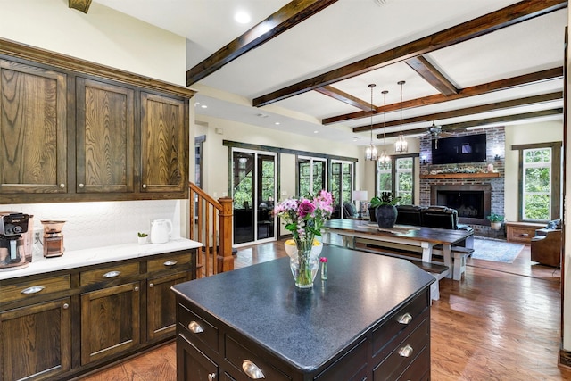 421 Dallas St, Argyle, TX 76226 - kitchen featuring a brick fireplace, beamed ceiling, wood finished floors, pendant lighting, and open floor plan