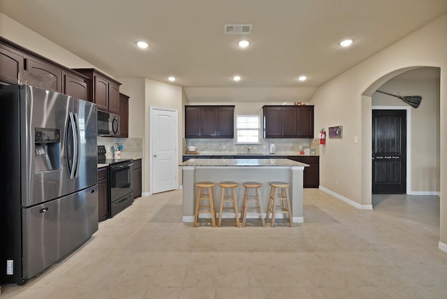 127 Pasture Ln, Decatur, TX 76234 - kitchen with black appliances, arched walkways, dark brown cabinetry, backsplash, and recessed lighting