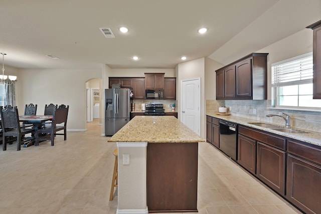127 Pasture Ln, Decatur, TX 76234 - kitchen with black appliances, arched walkways, tasteful backsplash, a kitchen island, and dark brown cabinetry