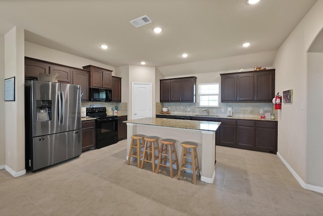 127 Pasture Ln, Decatur, TX 76234 - kitchen featuring black appliances, dark brown cabinets, decorative backsplash, a kitchen breakfast bar, and a center island