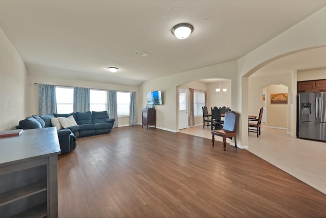 127 Pasture Ln, Decatur, TX 76234 - living area with arched walkways, plenty of natural light, wood finished floors, a chandelier, and a textured ceiling