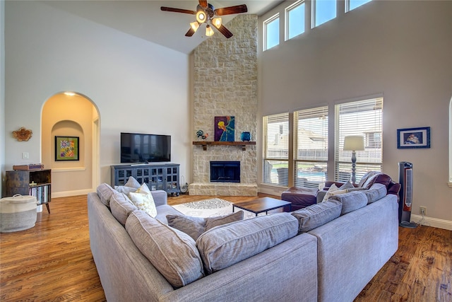 6341 Ashford Trl, Mesquite, TX 75181 - living area with high vaulted ceiling, a ceiling fan, wood finished floors, arched walkways, and a stone fireplace