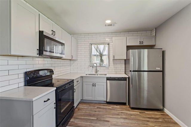 2628 Belhaven Dr, Mesquite, TX 75150 - kitchen with appliances with stainless steel finishes, decorative backsplash, light wood-style flooring, and white cabinetry