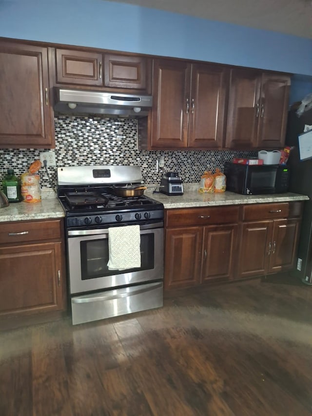 12634 Templeton Trl, Farmers Branch, TX 75234 - kitchen with stainless steel gas range oven, under cabinet range hood, black microwave, dark wood-type flooring, and tasteful backsplash