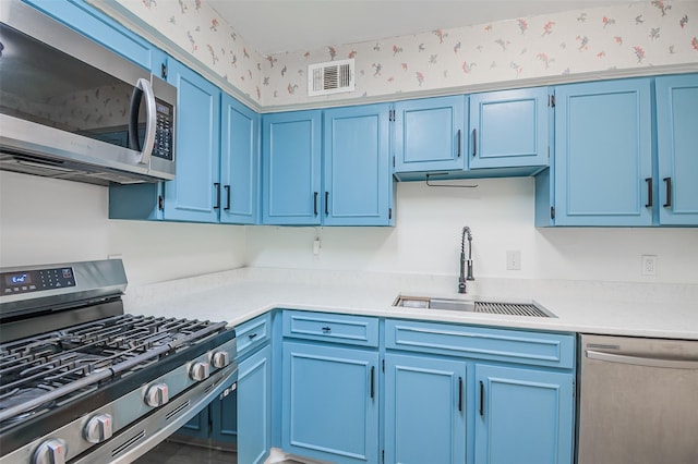 5907 Copperwood Ln Unit 1138, Dallas, TX 75248 - kitchen featuring stainless steel appliances, blue cabinets, wallpapered walls, and light countertops