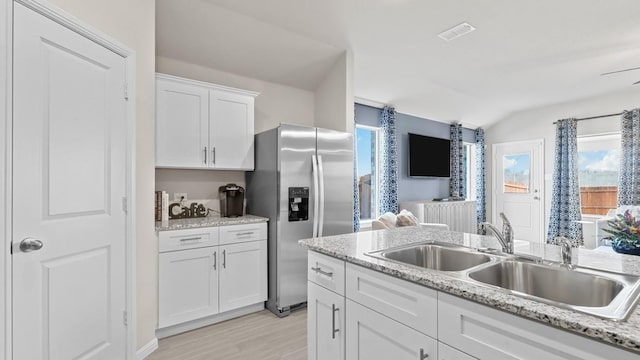 9453 Mint Hill Dr, Fort Worth, TX 76108 - kitchen with stainless steel refrigerator with ice dispenser, lofted ceiling, white cabinetry, light wood finished floors, and light stone counters