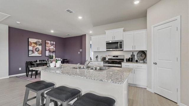 9453 Mint Hill Dr, Fort Worth, TX 76108 - kitchen featuring appliances with stainless steel finishes, light wood-style flooring, a kitchen bar, white cabinets, and recessed lighting
