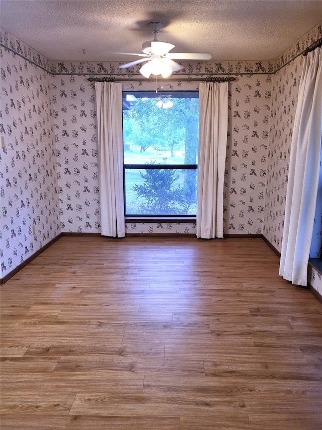 697 Highland Crest Dr, Hurst, TX 76054 - empty room featuring wallpapered walls, a textured ceiling, wood finished floors, and ceiling fan