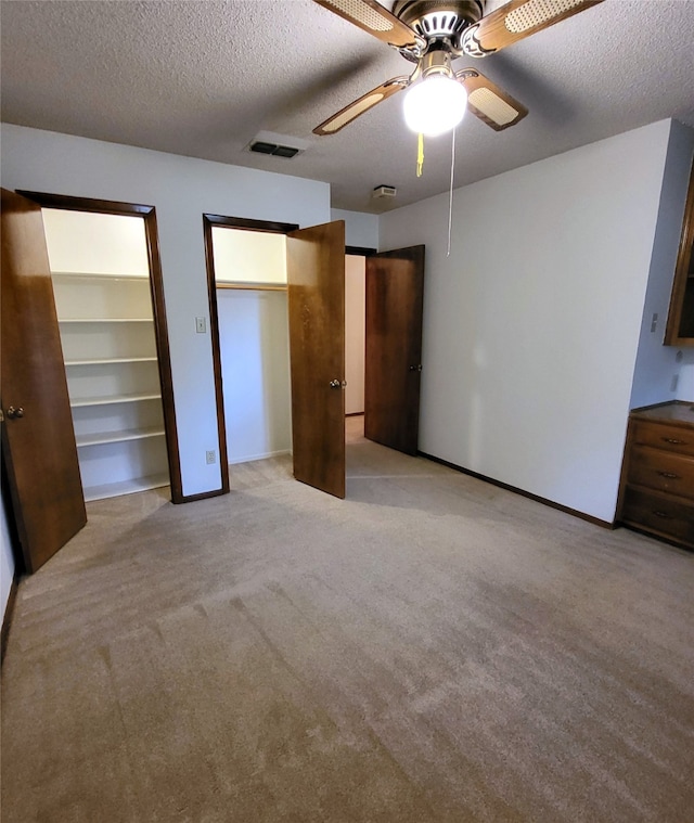 697 Highland Crest Dr, Hurst, TX 76054 - unfurnished bedroom with multiple closets, light colored carpet, a textured ceiling, and ceiling fan
