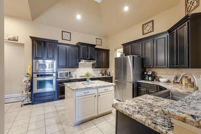 1970 Lake Forest Dr, Rockwall, TX 75087 - kitchen with appliances with stainless steel finishes, light stone countertops, under cabinet range hood, light tile patterned floors, and vaulted ceiling