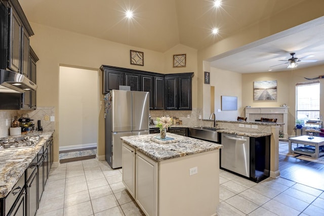 1970 Lake Forest Dr, Rockwall, TX 75087 - kitchen featuring appliances with stainless steel finishes, light tile patterned flooring, open floor plan, a peninsula, and vaulted ceiling