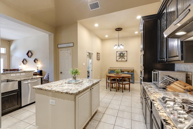 1970 Lake Forest Dr, Rockwall, TX 75087 - kitchen featuring appliances with stainless steel finishes, under cabinet range hood, light tile patterned flooring, a kitchen island, and decorative light fixtures