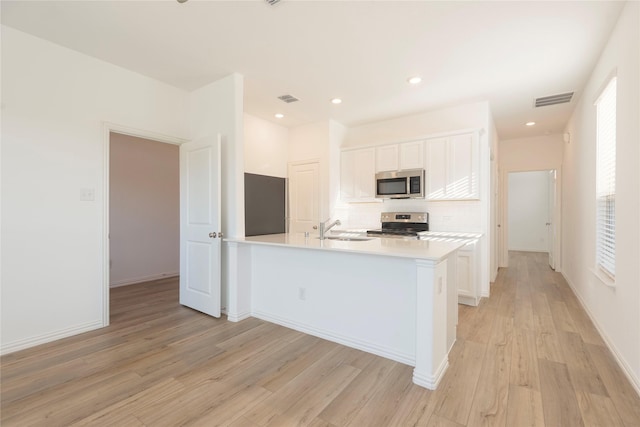 219 Autumn Sage Ln, Princeton, TX 75407 - kitchen with appliances with stainless steel finishes, decorative backsplash, light wood finished floors, white cabinetry, and recessed lighting