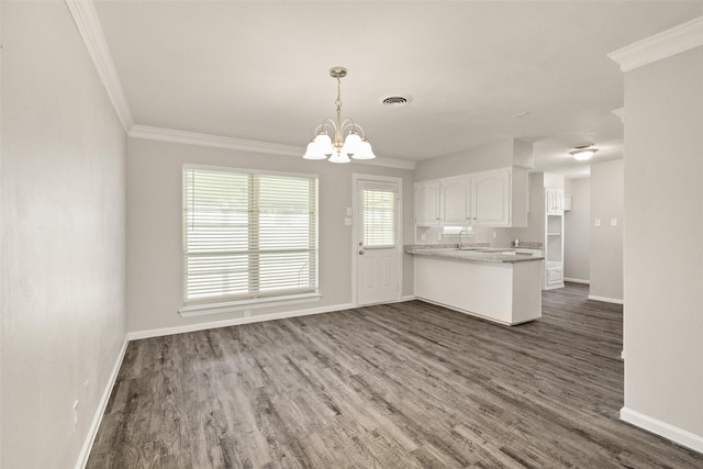 2405 Patricia Ln, Garland, TX 75041 - kitchen featuring white cabinets, a chandelier, ornamental molding, dark wood-type flooring, and decorative light fixtures