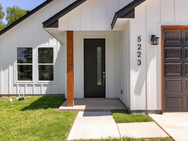 5223 Willie St, Fort Worth, TX 76105 - view of exterior entry featuring board and batten siding, a lawn, and a garage