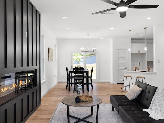 5223 Willie St, Fort Worth, TX 76105 - living room featuring a large fireplace, ceiling fan, light wood finished floors, recessed lighting, and a chandelier