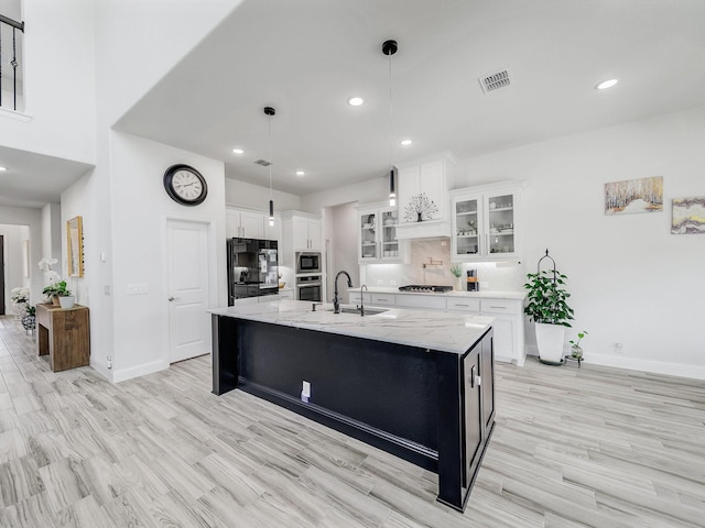 412 Navo Rd, Little Elm, TX 75068 - kitchen with appliances with stainless steel finishes, a kitchen island with sink, white cabinets, light wood-style floors, and recessed lighting
