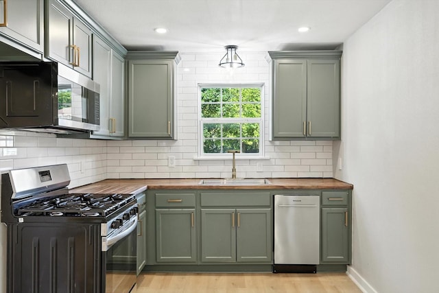 736 Wilson St, Denton, TX 76205 - kitchen featuring appliances with stainless steel finishes, green cabinets, wood counters, light wood-style floors, and recessed lighting