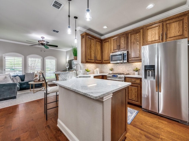 1901 Desoto Dr, Mckinney, TX 75072 - kitchen featuring stainless steel appliances, crown molding, a peninsula, brown cabinets, and a breakfast bar