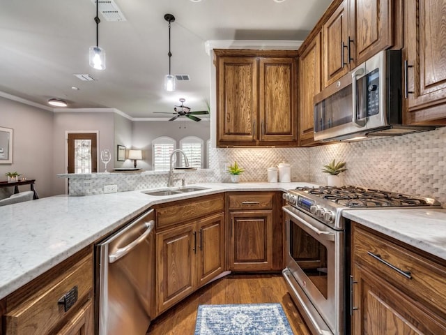 1901 Desoto Dr, Mckinney, TX 75072 - kitchen featuring stainless steel appliances, wood finished floors, brown cabinets, tasteful backsplash, and crown molding