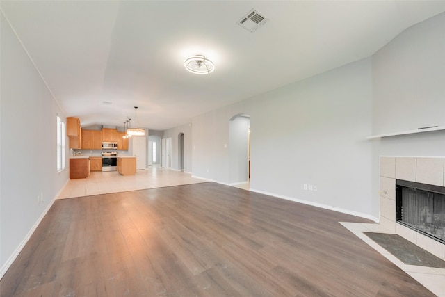 3016 Bryce Dr, Wylie, TX 75098 - unfurnished living room featuring vaulted ceiling, arched walkways, light wood-style floors, and a fireplace