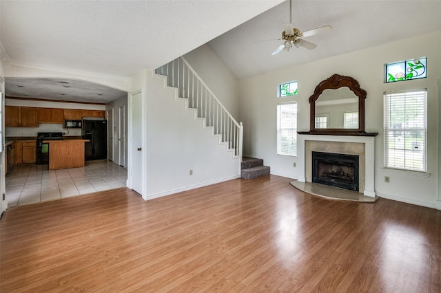 224 Iberis Dr, Arlington, TX 76018 - unfurnished living room with light wood-type flooring, a ceiling fan, a high end fireplace, stairway, and lofted ceiling