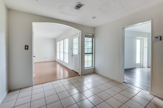 224 Iberis Dr, Arlington, TX 76018 - spare room featuring arched walkways, light tile patterned floors, and a textured ceiling