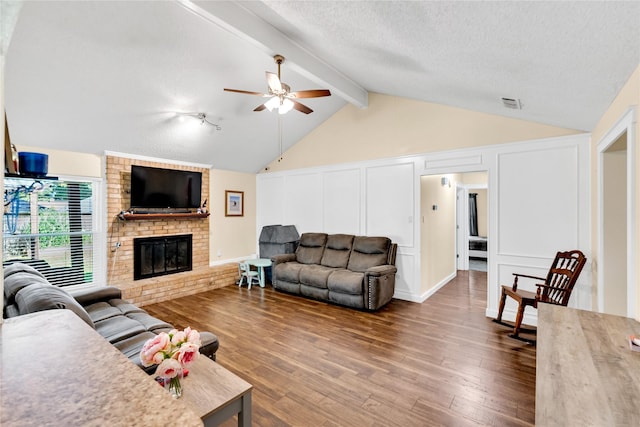 7612 Creekmoore Dr, Fort Worth, TX 76133 - living room featuring ceiling fan, a decorative wall, a brick fireplace, dark wood-style flooring, and a textured ceiling