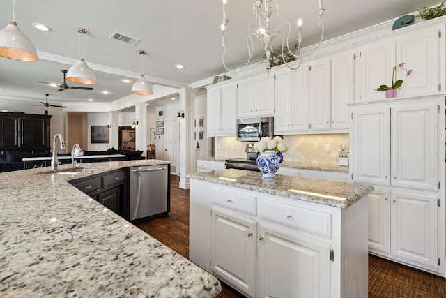 1212 Chandler Cir, Prosper, TX 75078 - kitchen featuring stainless steel appliances, ornate columns, open floor plan, white cabinets, and recessed lighting