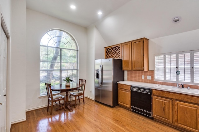 1908 Vantage Dr, Plano, TX 75075 - kitchen with black dishwasher, stainless steel fridge, light wood finished floors, vaulted ceiling, and brown cabinetry
