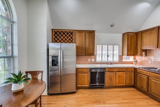1908 Vantage Dr, Plano, TX 75075 - kitchen with appliances with stainless steel finishes, vaulted ceiling, brown cabinets, light wood-style flooring, and decorative backsplash