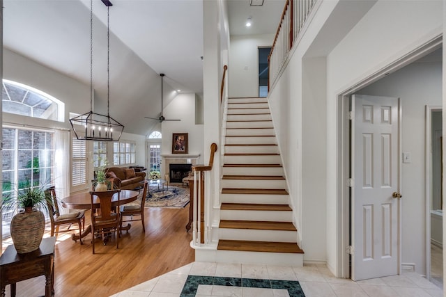 1908 Vantage Dr, Plano, TX 75075 - stairs with high vaulted ceiling, a fireplace, ceiling fan, and tile patterned floors