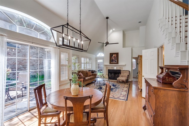 1908 Vantage Dr, Plano, TX 75075 - dining space featuring high vaulted ceiling, light wood-style floors, a fireplace, ceiling fan, and stairs