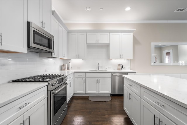 8538 Church St, Frisco, TX 75034 - kitchen with appliances with stainless steel finishes, crown molding, white cabinetry, backsplash, and dark wood-style flooring