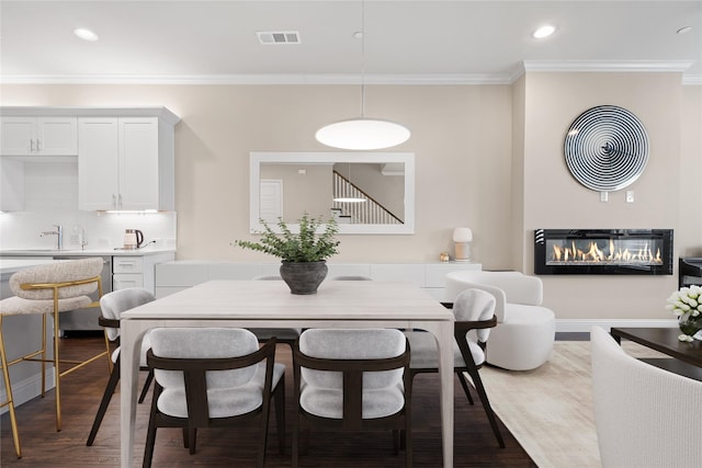 8538 Church St, Frisco, TX 75034 - dining area featuring crown molding, wood finished floors, a glass covered fireplace, and recessed lighting