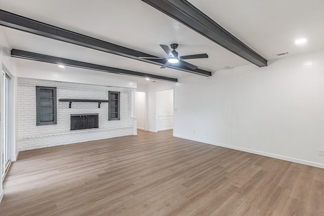 1517 Amherst Dr, Plano, TX 75075 - unfurnished living room featuring light wood-style floors, ceiling fan, beamed ceiling, a brick fireplace, and brick wall