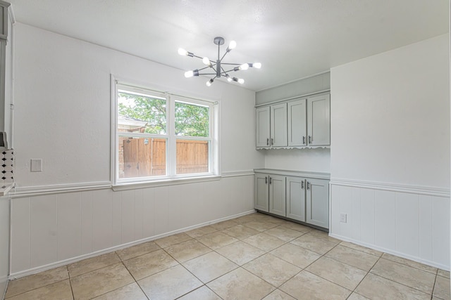 1517 Amherst Dr, Plano, TX 75075 - unfurnished dining area featuring a chandelier, a wainscoted wall, and light tile patterned floors