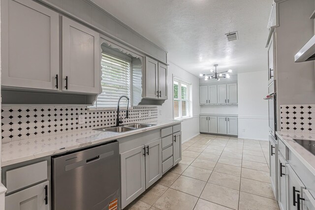 1517 Amherst Dr, Plano, TX 75075 - kitchen with appliances with stainless steel finishes, tasteful backsplash, a chandelier, light tile patterned floors, and gray cabinets
