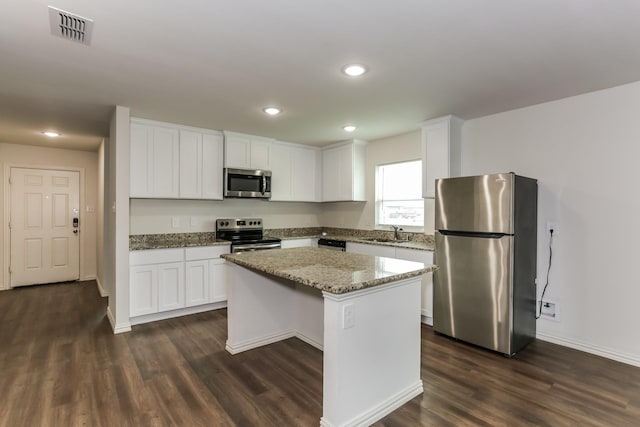 2906 Emma Ln, Mabank, TX 75147 - kitchen with appliances with stainless steel finishes, a center island, dark wood-style floors, white cabinets, and recessed lighting