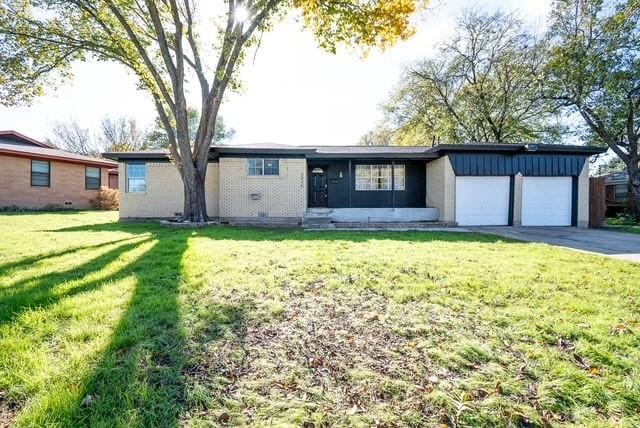 5920 Tourist Dr, North Richland Hills, TX 76117 - single story home featuring board and batten siding, a garage, asphalt driveway, and a front lawn