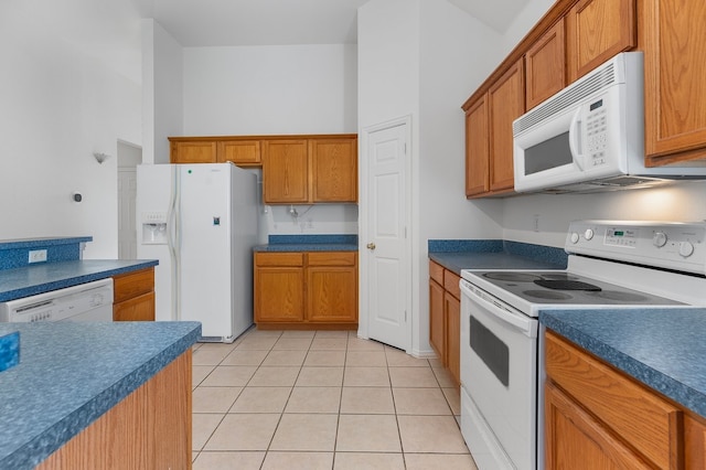 6716 Armstrong Ct, Fort Worth, TX 76137 - kitchen with white appliances, light tile patterned floors, brown cabinetry, and dark countertops
